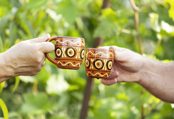 The hands holding wine mugs and making cheers - Photo, Image