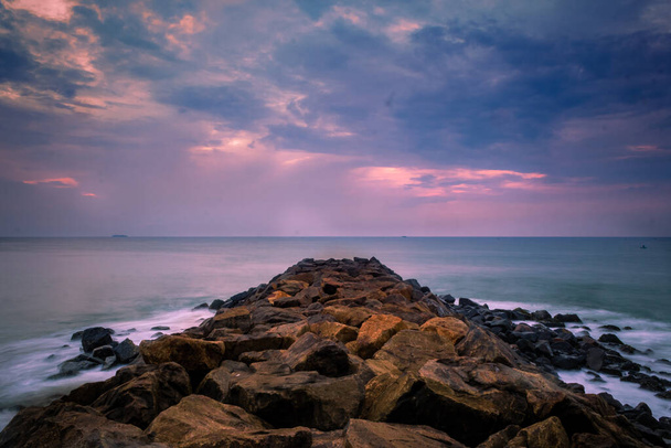 長い露出でビーチの上に美しい日の出。インドの岩場から要素の日の出と波の写真を移動します。波ブレーカ岩、スローシャッター海波と岩写真. - 写真・画像