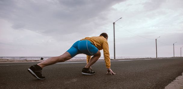 Runner man ready to run on the road from a low start - 写真・画像