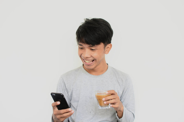 Портрет чоловіка з щасливим виразом, який дивиться на свій мобільний телефон під час носіння кави
 - Фото, зображення