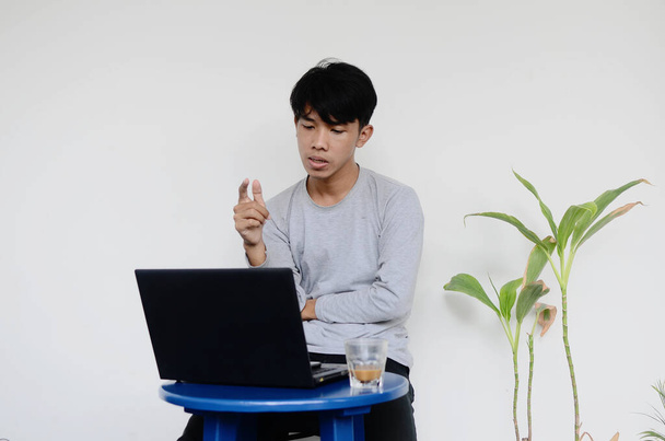 junger asiatischer Mann sitzt am Laptop mit düsterem Gesicht - Foto, Bild