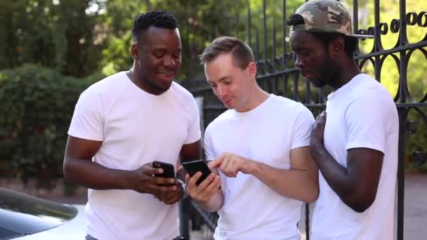 Três estudantes multirraciais se comunicam, olham para o telefone e riem - Filmagem, Vídeo