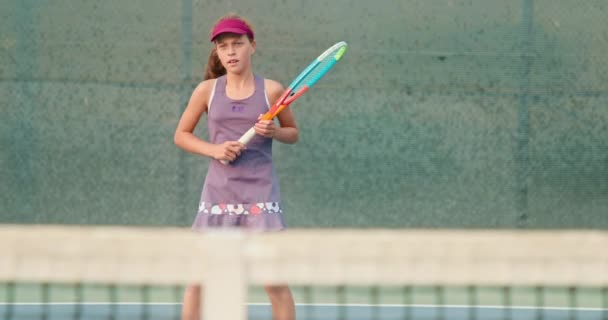 Urheilullinen tyttö pelaa tennistä kentällä. Aktiivinen teini on lyömällä pallo maila - Materiaali, video