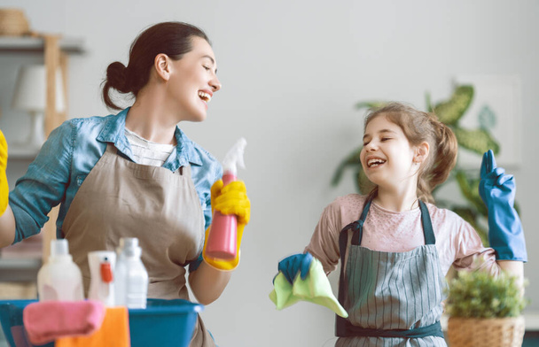 Happy family at home. Mother and daughter doing the cleaning in the house. A young woman and child girl are dusting. Cute little helper. - Фото, зображення