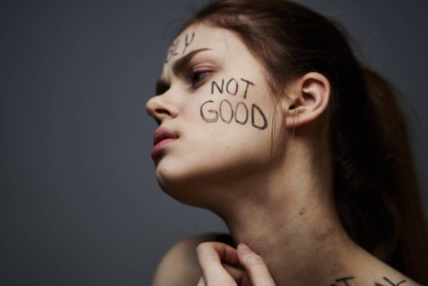 Emotionale Frau mit Inschriften auf Körper verärgert über Frustration grauen Hintergrund - Foto, Bild