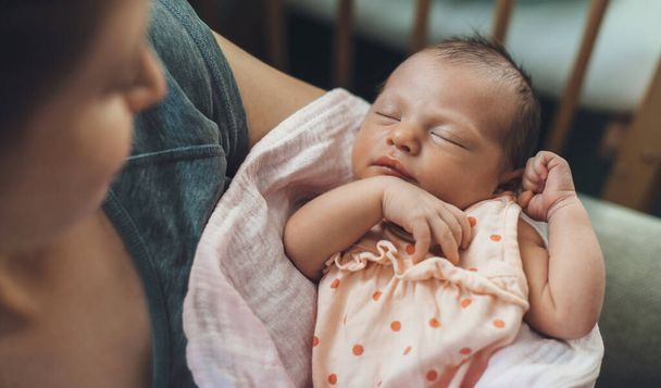 Neugeborenes Baby schläft in Sicherheit, während Mutter es hält und anlächelt - Foto, Bild