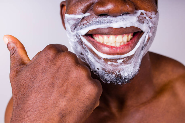 latin hispanic man with razor and shaving foam on his face studio white isolate background - Foto, Bild
