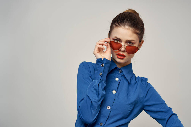 Portrait of a woman in sunglasses and a blue shirt on a light background cropped view of Model Copy Space - Foto, Imagen