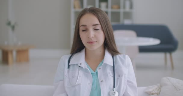 Kijkend naar de camera luisterende vrouwelijke arts kijkt naar de camera en luistert naar de patiënt. Een videoconferentie luisteraar. Portret van een arts - Video