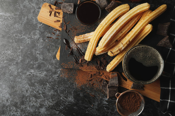 Έννοια του γεύματος με churros και σοκολάτα σε σκούρο τραπέζι - Φωτογραφία, εικόνα