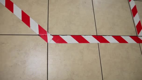 Op de vloer wordt een rood-witte waarschuwingstape aangebracht voor sociale afstand. - Video