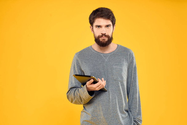 Emotional man with tablet in hands technology internet device lifestyle yellow background - 写真・画像