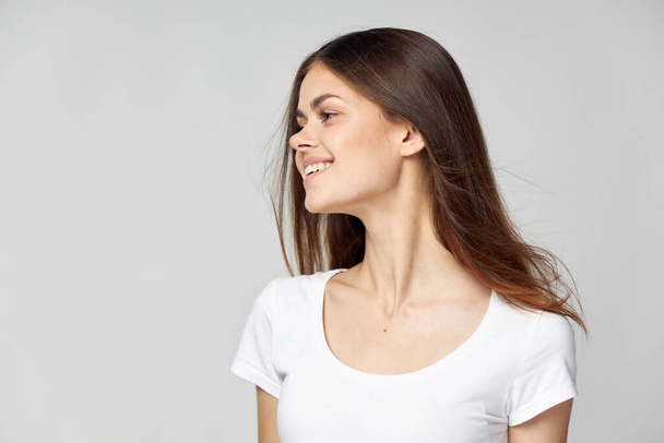 Aantrekkelijke vrouw met los haar in een wit T-shirt lacht en draait haar hoofd - Foto, afbeelding