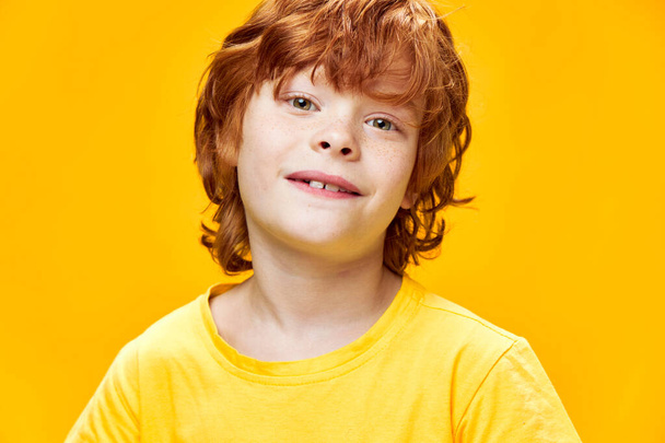Uśmiechnięty chłopiec w żółtej koszulce z rudymi włosami - Zdjęcie, obraz
