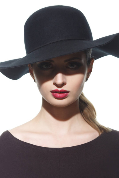 Fashion portrait of a silhouette of a girl in a hat with wide brim with a shadow in front of her eyes. - Foto, Imagem