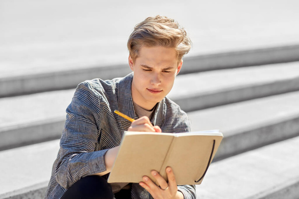 young man with notebook or sketchbook in city - Foto, Imagen