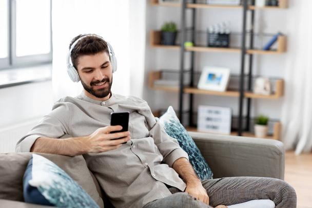 man in headphones listening to music on smartphone - Φωτογραφία, εικόνα