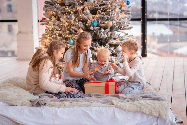 Happy kids having fun and opening presents near christmas tree. - Foto, Bild