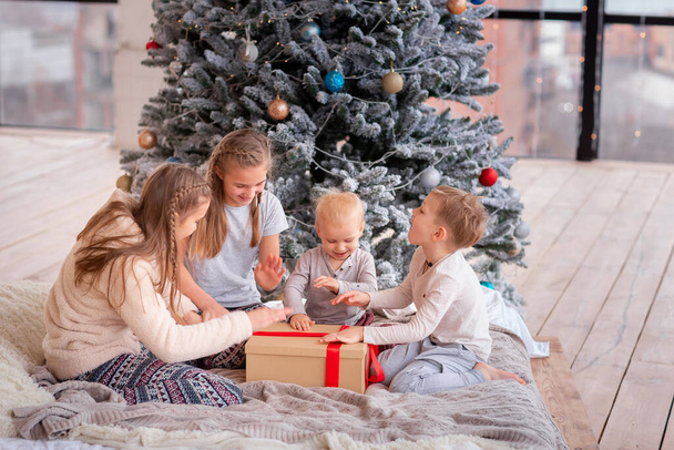 Happy kids having fun and opening presents near christmas tree. - Foto, imagen