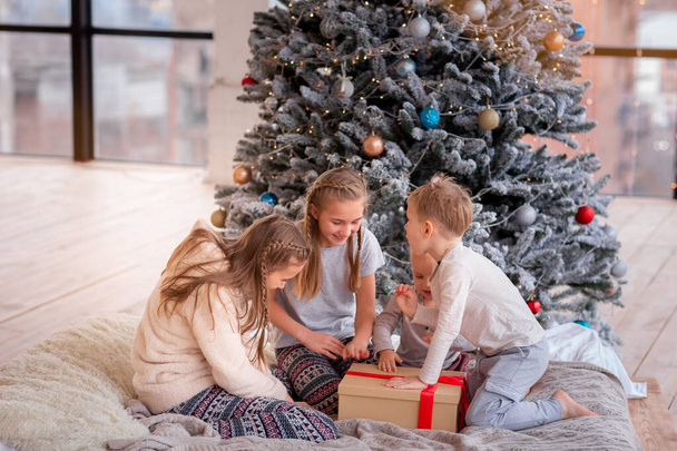 Happy kids having fun and opening presents near christmas tree. - Zdjęcie, obraz
