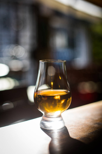 Color de cerca disparó un vaso de whisky Glencairn en una mesa de madera, con poca profundidad de campo. - Foto, imagen