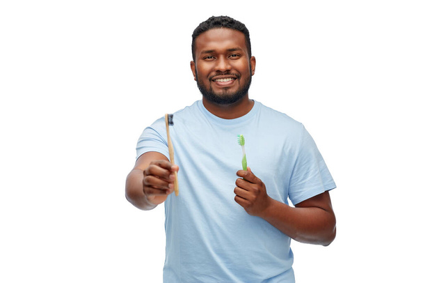 african man with wooden and plastic toothbrushes - Foto, afbeelding