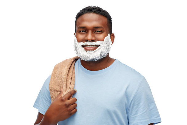 homme africain souriant avec crème à raser et serviette - Photo, image