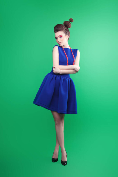 Beautiful girl in a blue dress in the style of pin-up on a green background in full growth - Foto, Imagem