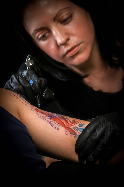 Tatuaggio femminile che fa tatuaggio sul braccio di un uomo
 - Foto, immagini