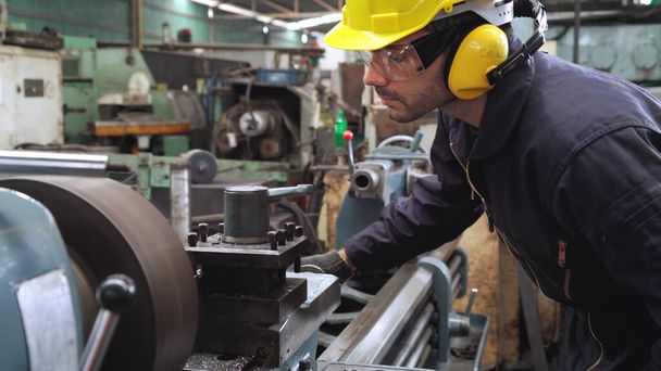 Fabrika atölyesinde makine kullanan akıllı bir fabrika işçisi - Fotoğraf, Görsel