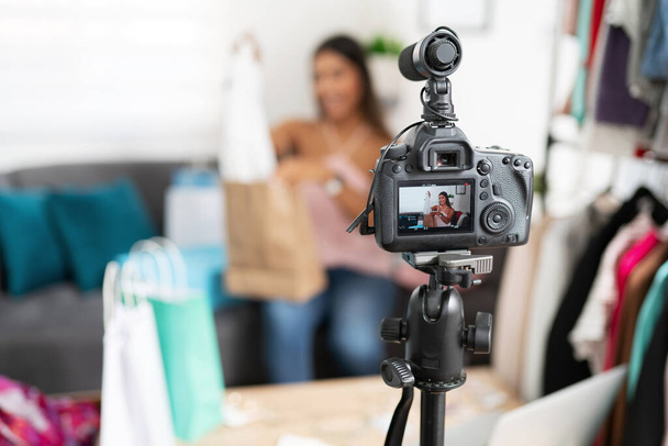 Closeup of a dslr camera recording a fashion video blogger while she shows some clothes to her followers - Photo, Image