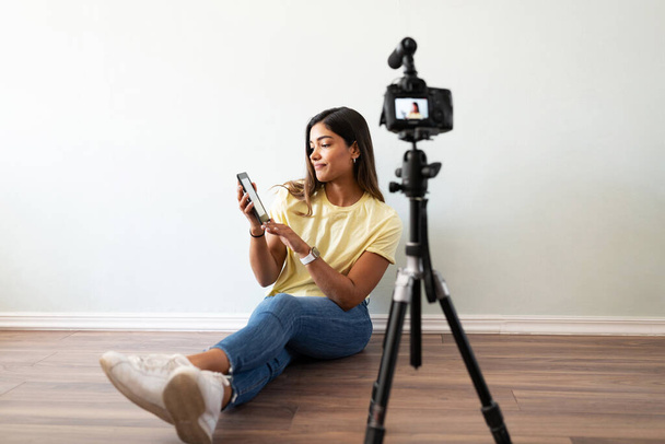 Young woman recording a video and talking about a book she just read and sharing her thoughts and opinion with her audience - Photo, Image