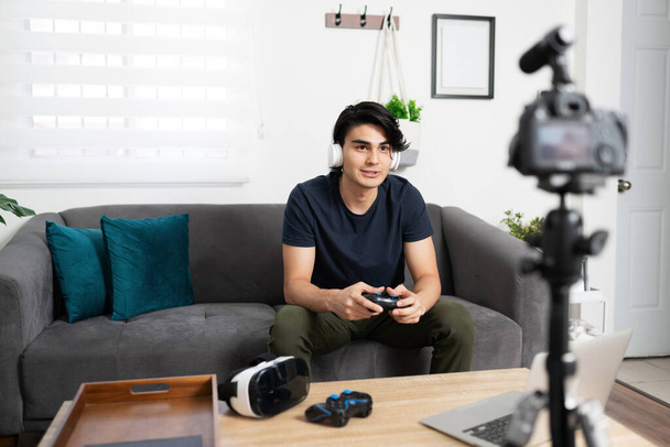 Videoblogger und Influencer trägt Kopfhörer und überprüft Videospiele vor der Kamera für einige seiner Zuschauer - Foto, Bild