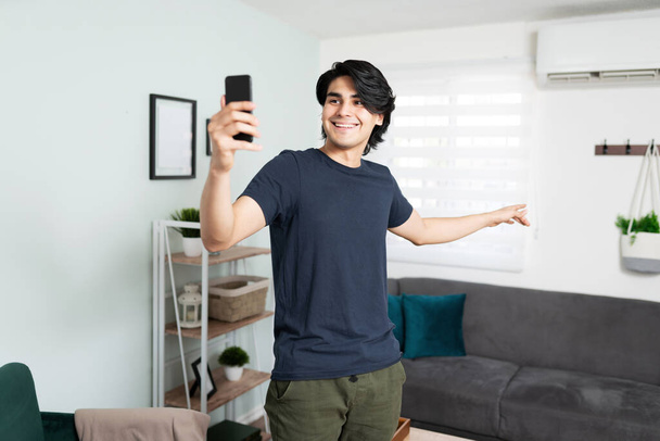 Komea latino vaikuttaja jakaa live video sisätilojen hänen huoneisto ja hymyilee - Valokuva, kuva