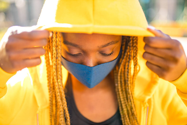 latijn Braziliaanse vrouw in gele hoody met gele vlechten dreadlocks in de straat nam naar het openbare park en de straten om te protesteren feminisme - Foto, afbeelding