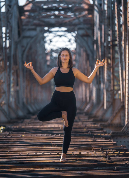 Girl practices yoga on an old abandoned bridge - Φωτογραφία, εικόνα