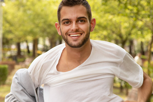 портрет молодого человека на улице, снимающего свитер - Фото, изображение