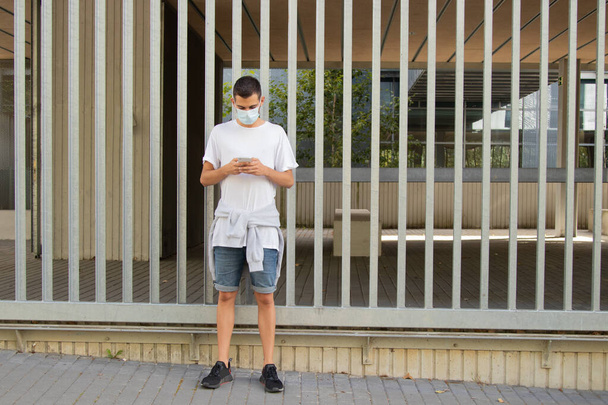 młody człowiek w mieście z maską i telefonem komórkowym - Zdjęcie, obraz