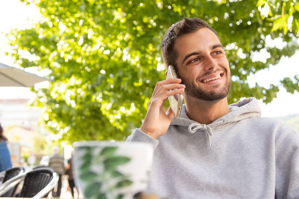 fiatal férfi a kávézó teraszán mobiltelefonnal - Fotó, kép