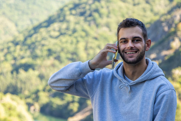 young man with mobile phone in nature outdoors - Фото, изображение