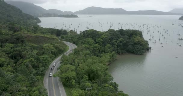 voitures sur la route et bateaux à Saco da Ribeira à Ubatuba, Sao Paulo, Brésil, mouvement d'élévation - Séquence, vidéo