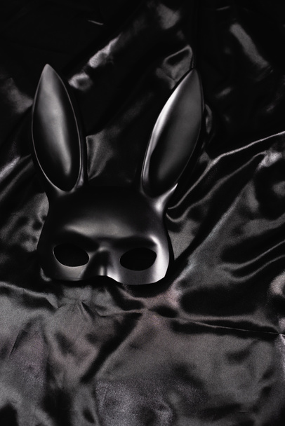 Top view of black bdsm rabbit mask on satin bedding  - Fotoğraf, Görsel
