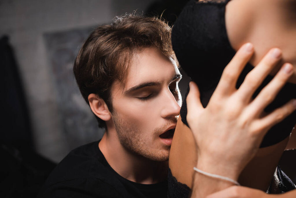 Passionate man kissing belly of sensual woman on blurred foreground at home  - Фото, изображение