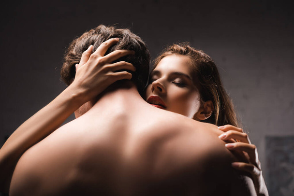 Mujer apasionada con labios rojos abrazando novio sin camisa  - Foto, Imagen