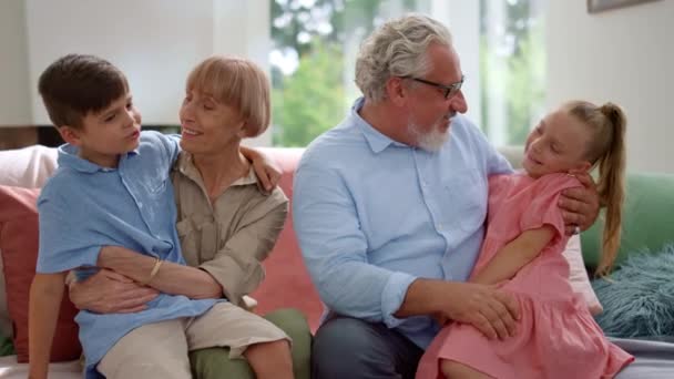 Boldog nagyapa és nagymama ül a kanapén unokák ölében - Felvétel, videó