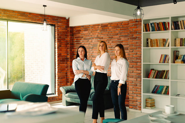 Career business women group of three people looking strong tough and showing confidence with crossed arms standing in modern office. Smiling mature professional business ladies. - Valokuva, kuva