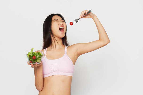 Schlanke Frau in Sportbekleidung und Salat im Teller - Foto, Bild