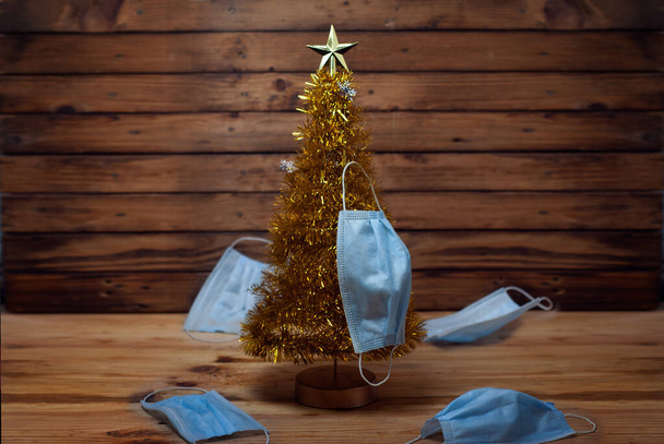Salgın ve Noel ağacı, ahşap arka planda tıbbi maskeli Noel ağacı, - Fotoğraf, Görsel