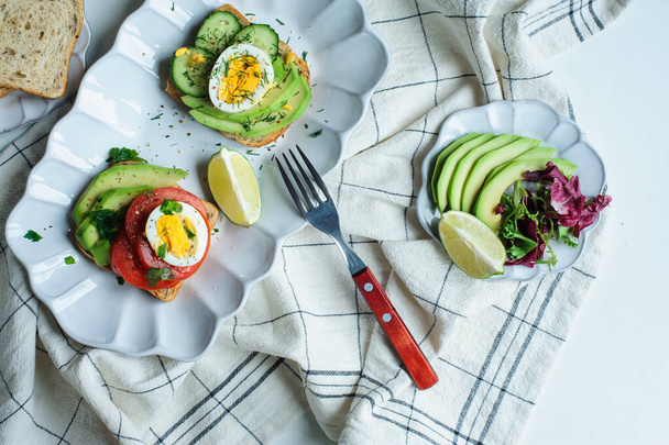 healthy vegetarian breakfast, avocado toast with cucumber, eggs, tomato and greean salad on wholegrain bread - Photo, Image
