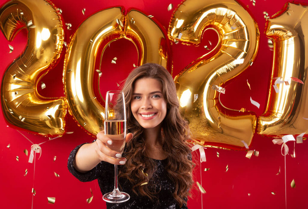 Kaunis nuori nainen paahtoleipää lasi samppanjaa uudenvuoden osapuoli yli punainen studio tausta kulta ilmapalloja - Valokuva, kuva